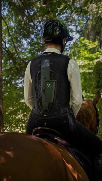 A rider on a horse is wearing a Horse Pilot E-Twist'Air airbag vest. A rider on a horse in the forest is wearing a Horse Pilot E-Twist'Air airbag vest_ from behind.