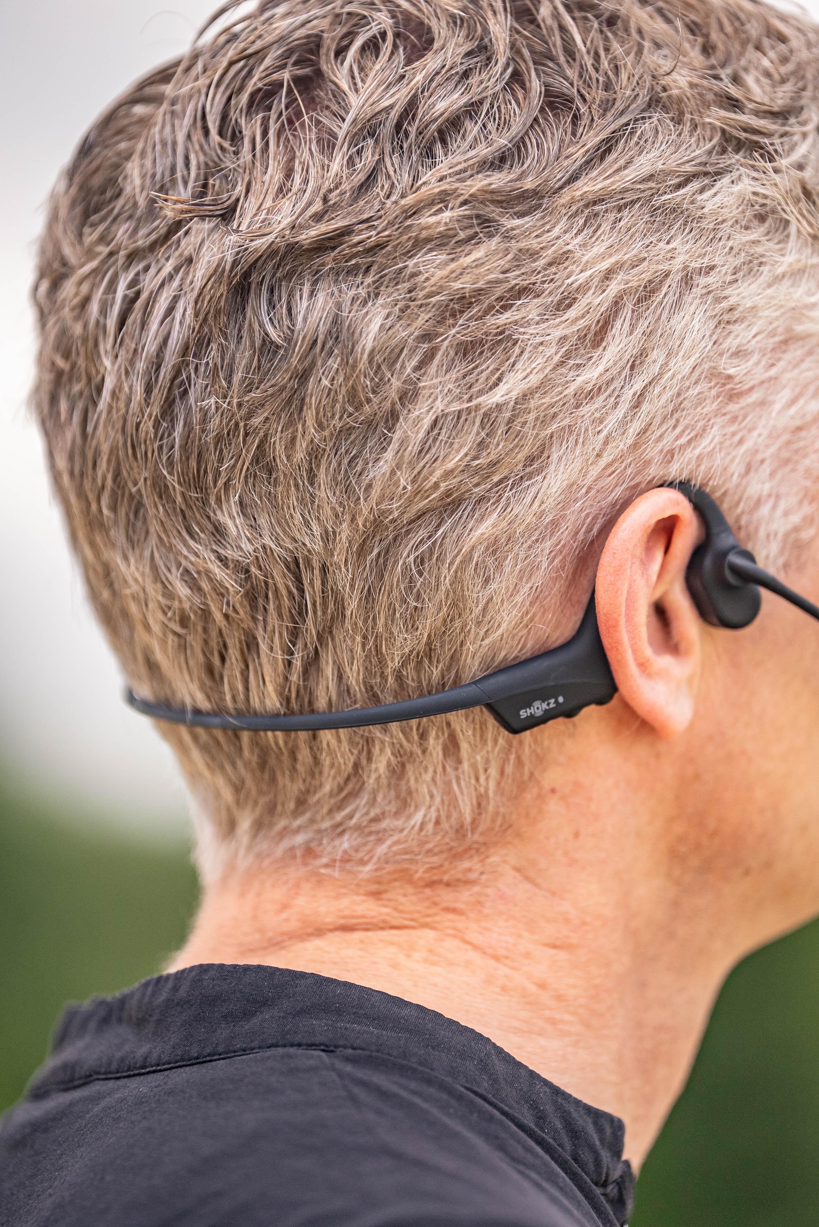 Shokz-Knochenschall-Headsets am Hinterkopf einer Person.