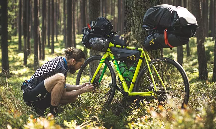 Ein Radfahrer beugt sich über sein Fahrrad, um eine Reparatur vorzunehmen. Ein Radfahrer beugt sich über sein hellgrünes Fahrrad, um eine Reparatur an seinem Hinterrad vorzunehmen.