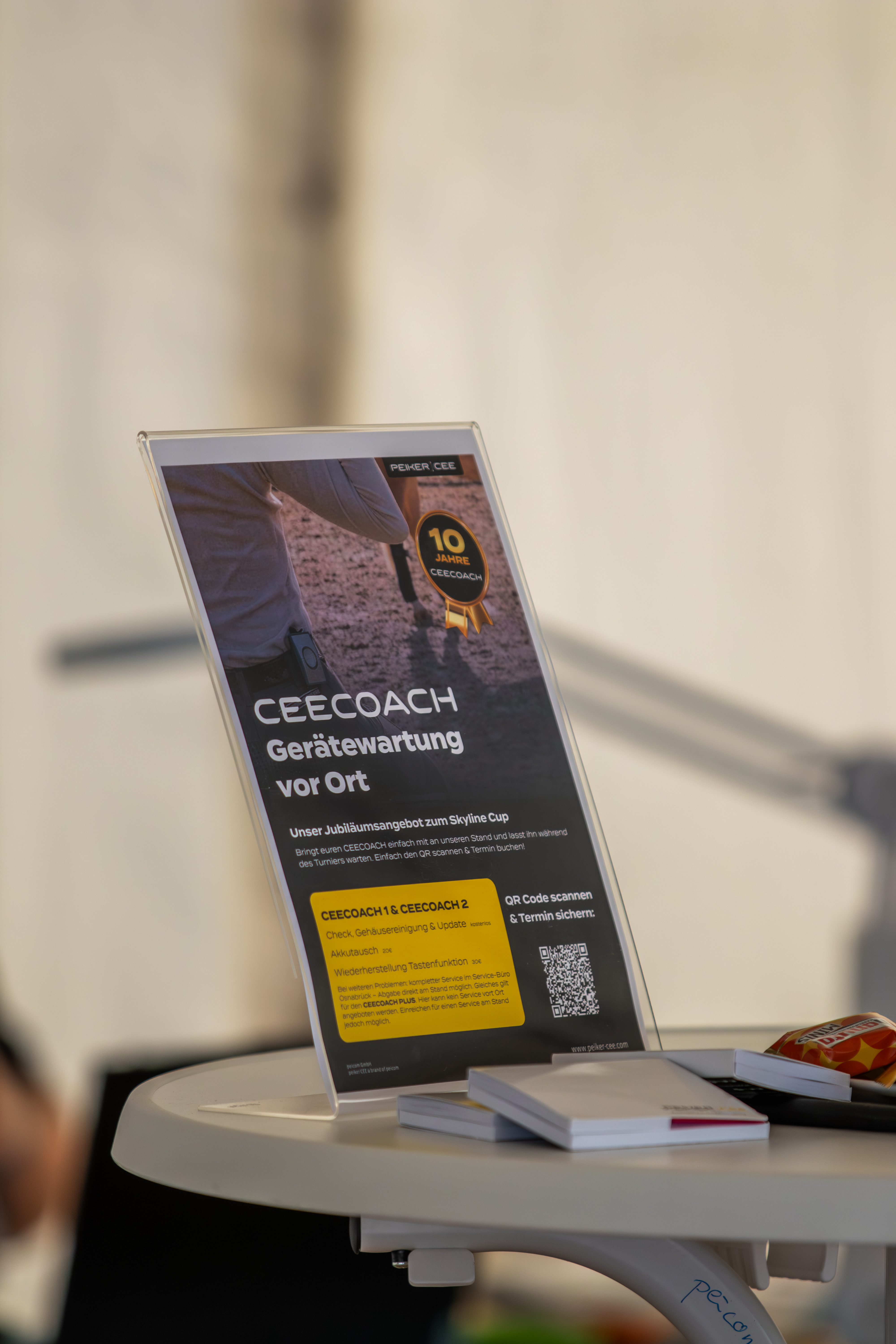Ein Tischaufsteller von peiker CEE mit der Aufschrift „CEECOACH Gerätewartung vor Ort“ und einem Siegel zu „10 Jahre CEECOACH“.