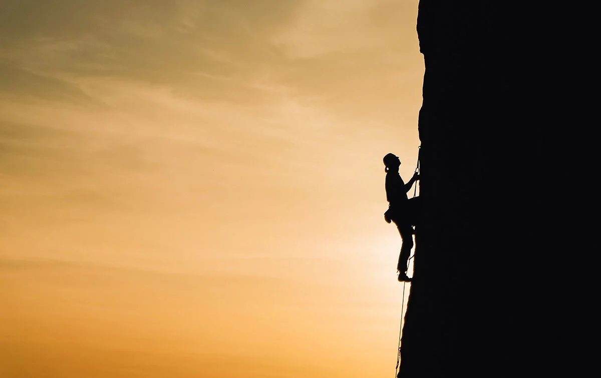Climbing-rock face-sunset-silhouette-outdoor sport. Climbing at sunset, silhouette of a person.
